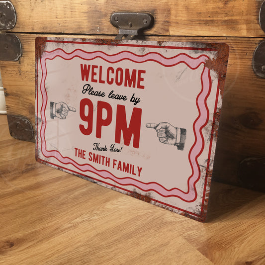 Vintage-style sign on a wooden surface with 'Welcome, please leave by 9PM' text.