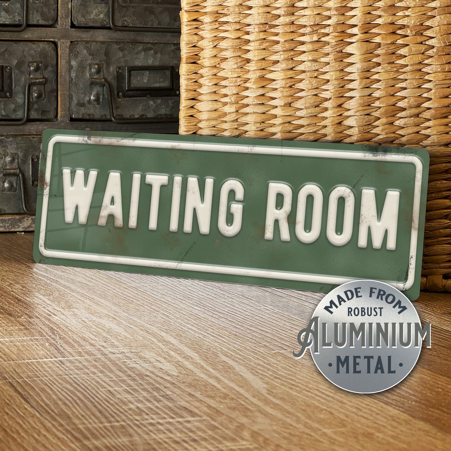 Green 'WAITING ROOM' sign with metallic finish on a wooden surface.