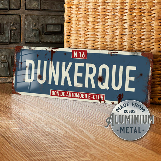 Vintage-style metal sign with 'Dunkerque' text on a wooden surface.