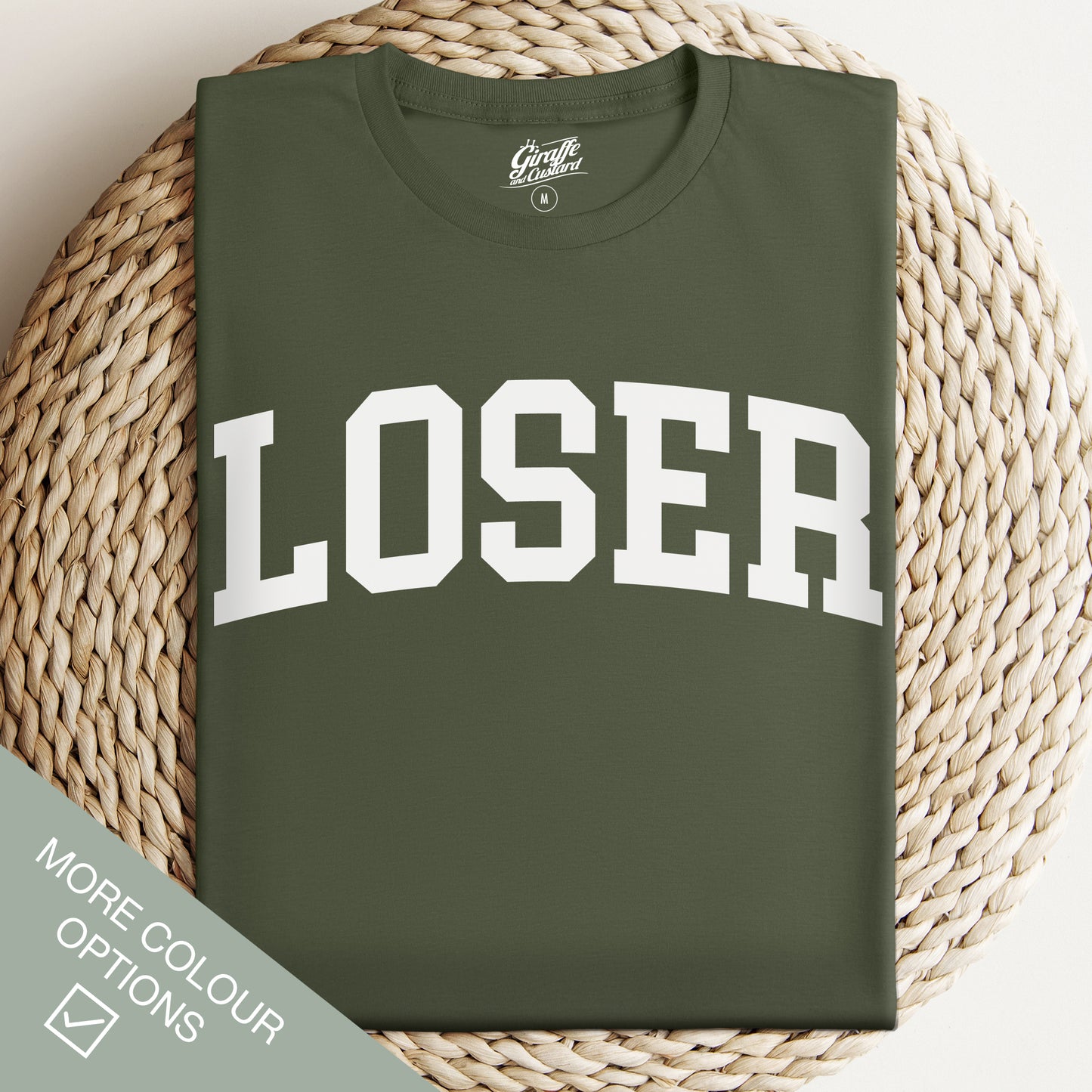 Green t-shirt with 'LOSER' printed on it, displayed on a woven surface.