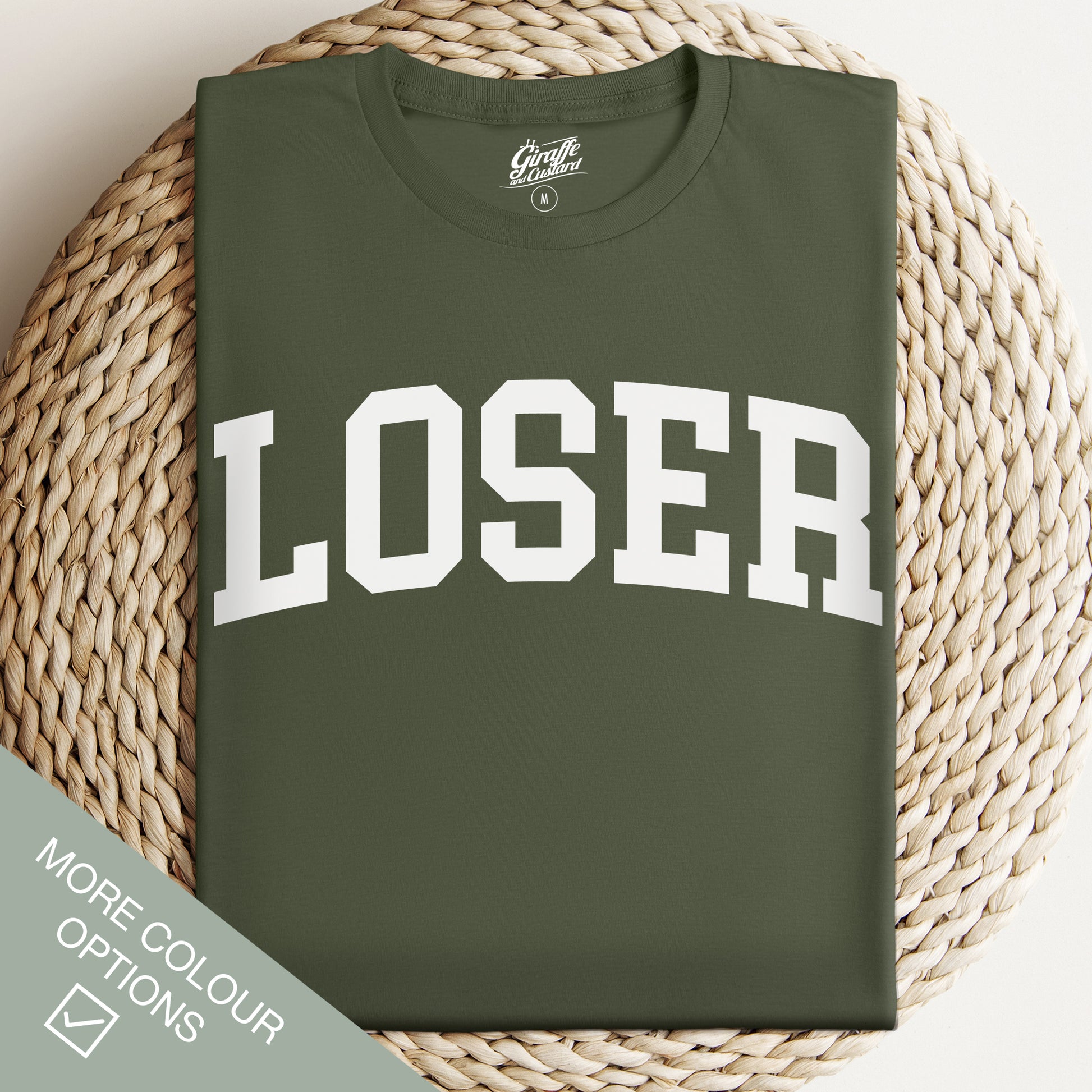Green t-shirt with 'LOSER' printed on it, displayed on a woven surface.