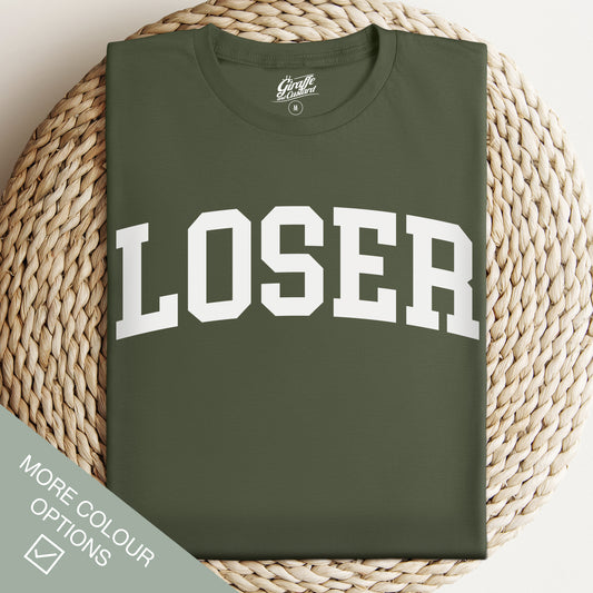 Green t-shirt with 'LOSER' printed on it, displayed on a woven surface.