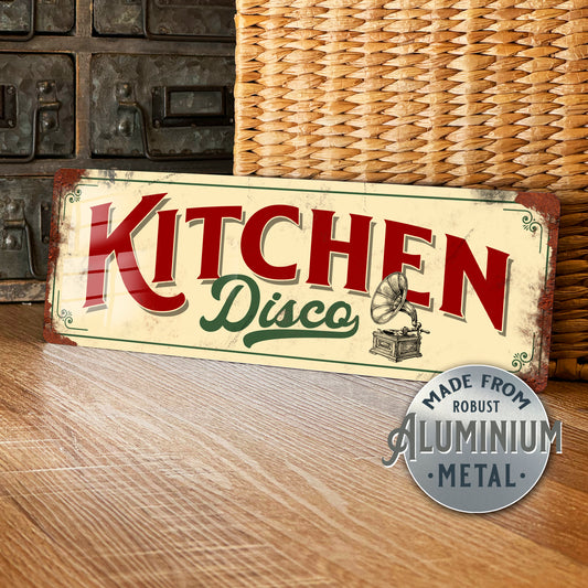 Decorative sign with 'Kitchen Disco' text on a wooden surface, featuring a wicker basket and metallic background.