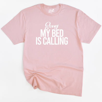 Pink t-shirt with 'Sorry My Bed Is Calling' text on a white background