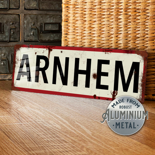 Vintage-style sign with 'ARNHEM' text on a wooden surface, featuring a metal plaque indicating material.