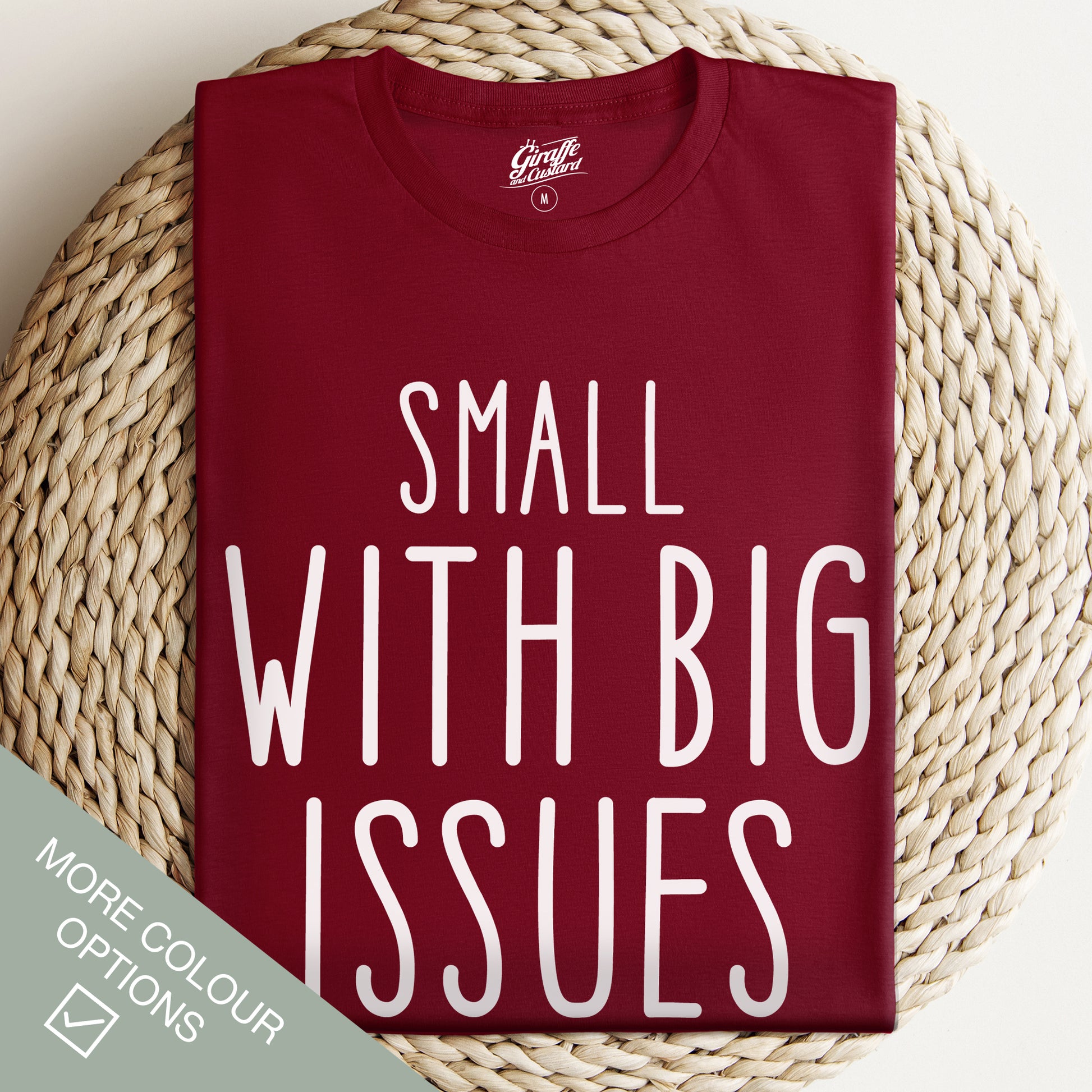 Maroon t-shirt with 'Small with Big Issues' text on a woven surface