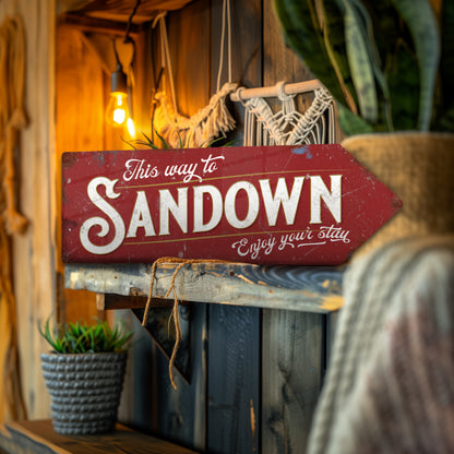 Decorative sign with 'This way to Sandown' text in a rustic setting.