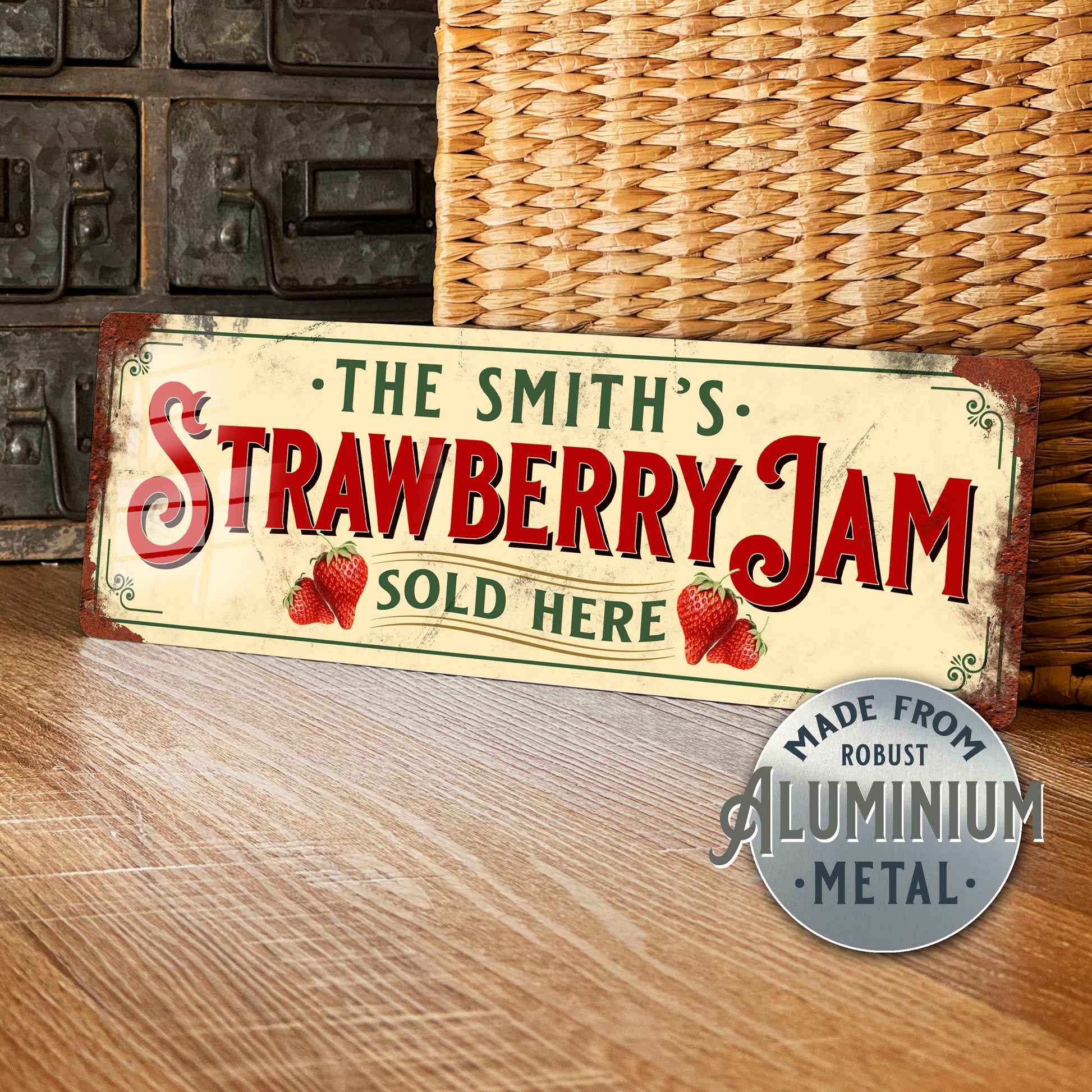 Vintage-style sign reading 'The Smith's Strawberry Jam Sold Here' on a wooden surface with a wicker basket in the background.