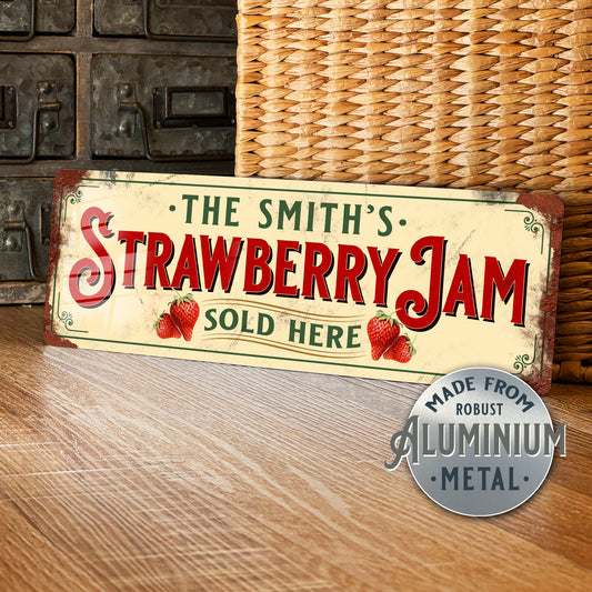 Vintage-style sign reading 'The Smith's Strawberry Jam Sold Here' on a wooden surface with a wicker basket in the background.