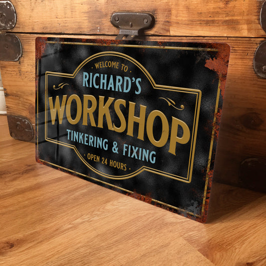 Metal sign reading 'Welcome to Richard's Workshop Tinkering & Fixing Open 24 Hours' on a wooden surface.